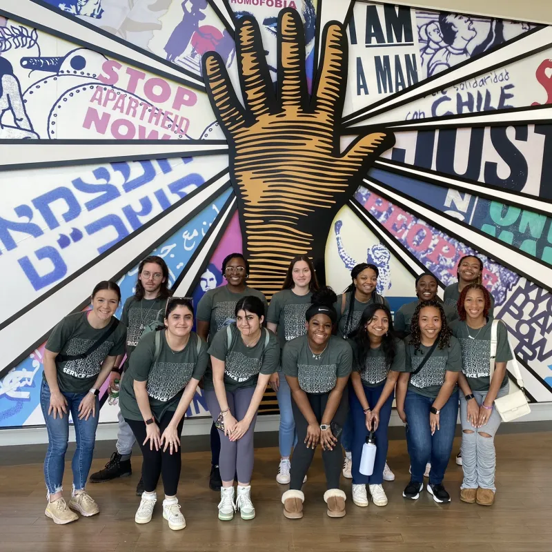 Students gathered in front of indoor painted justice mural
