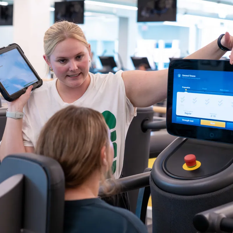 Someone helping a student figure out how to use the EGYM equipment