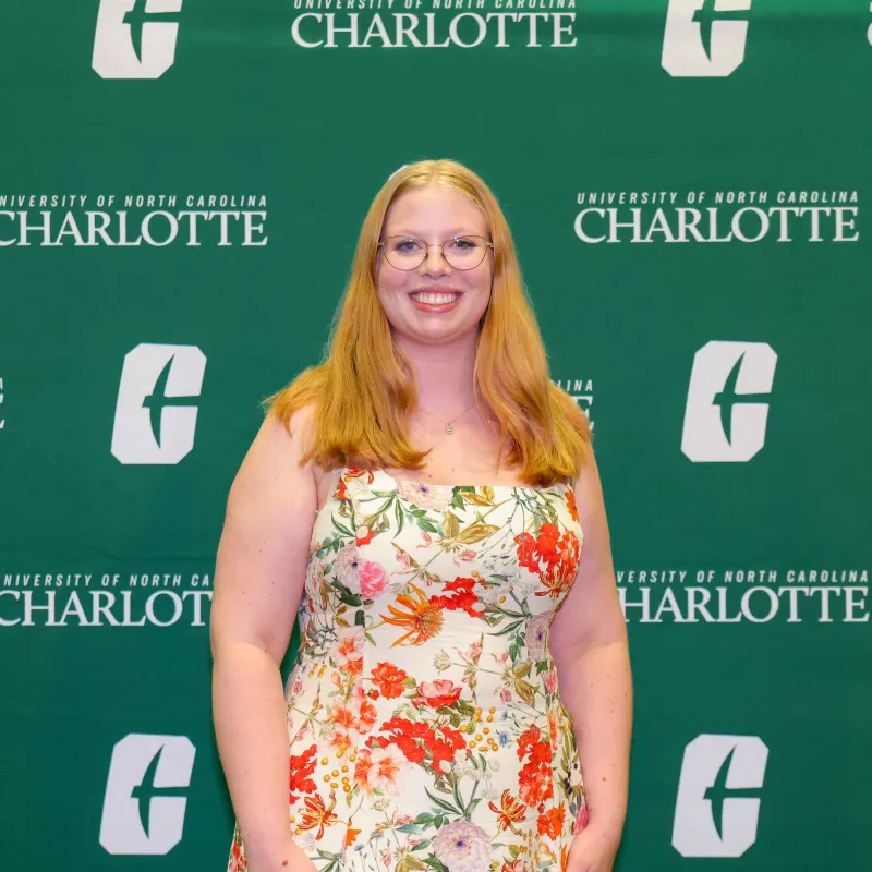 Emily Pierce smiling in front of a UNC Charlotte backdrop