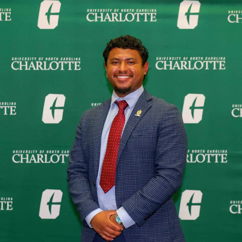 Erik Contreras Valdivia smiling in front of a UNC Charlotte backdrop