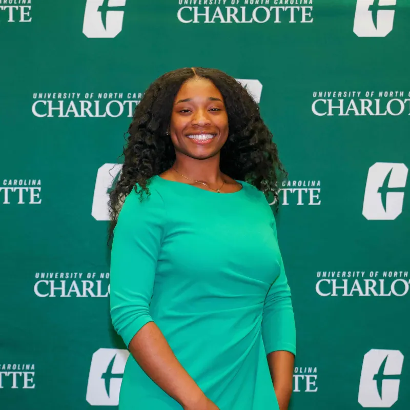 Eunice Okyere smiling in front of a UNC Charlotte backdrop