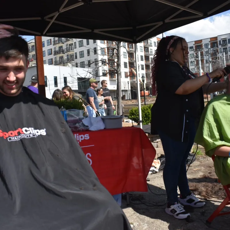 Two fraternity members shaving their heads to promote cancer research.