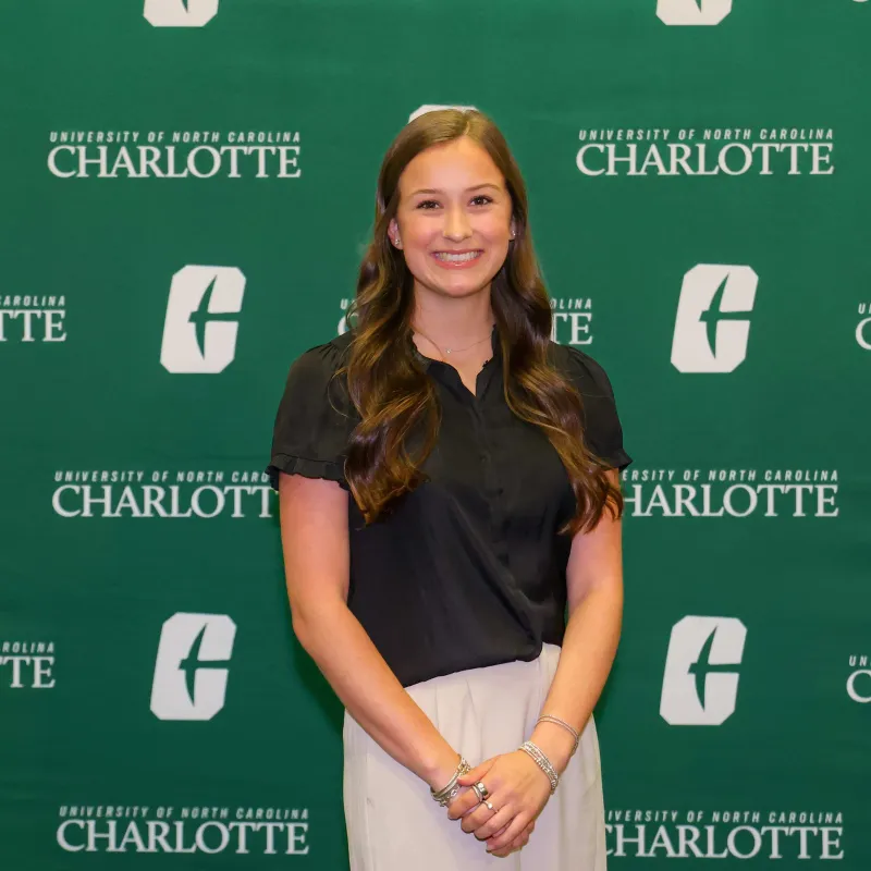 Kamryn Latino smiling in front of the UNC Charlotte backdrop