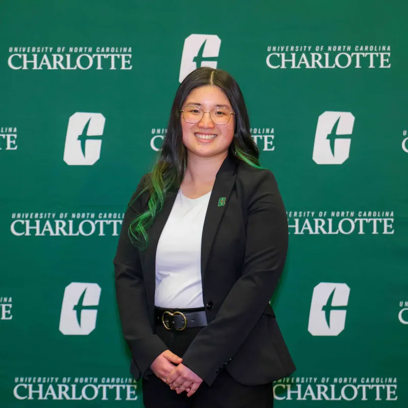 Lexue Zhao smiling in front of the UNC Charlotte backdrop