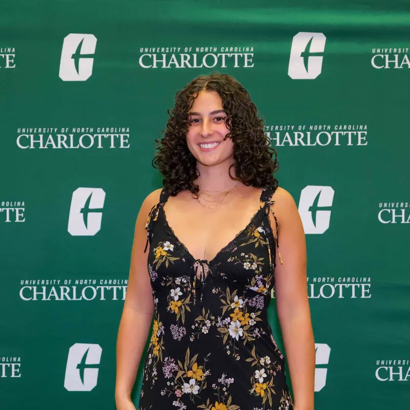Macy Klein smiling in front of a UNC Charlotte backdrop