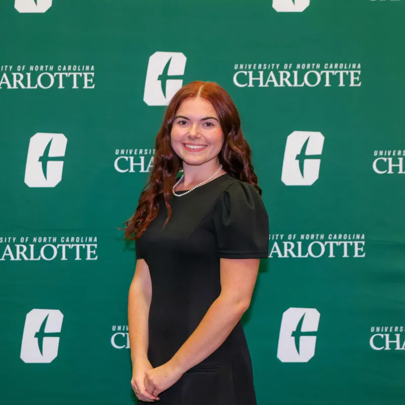 Madison File smiling in front of a UNC Charlotte backdrop
