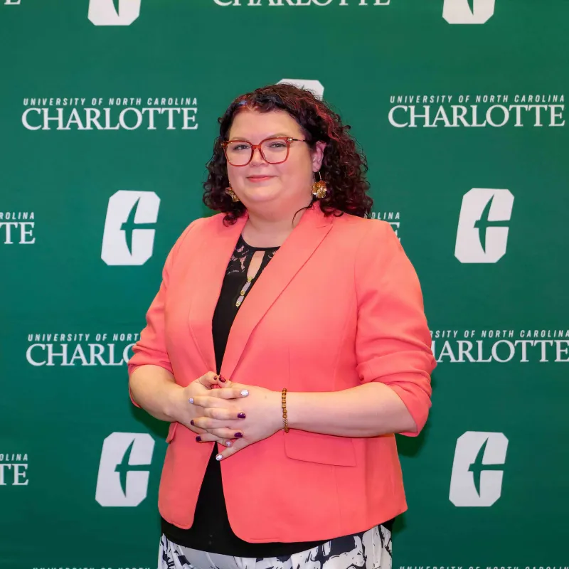 Megan Mitchem smiling in front of the UNC Charlotte backdrop