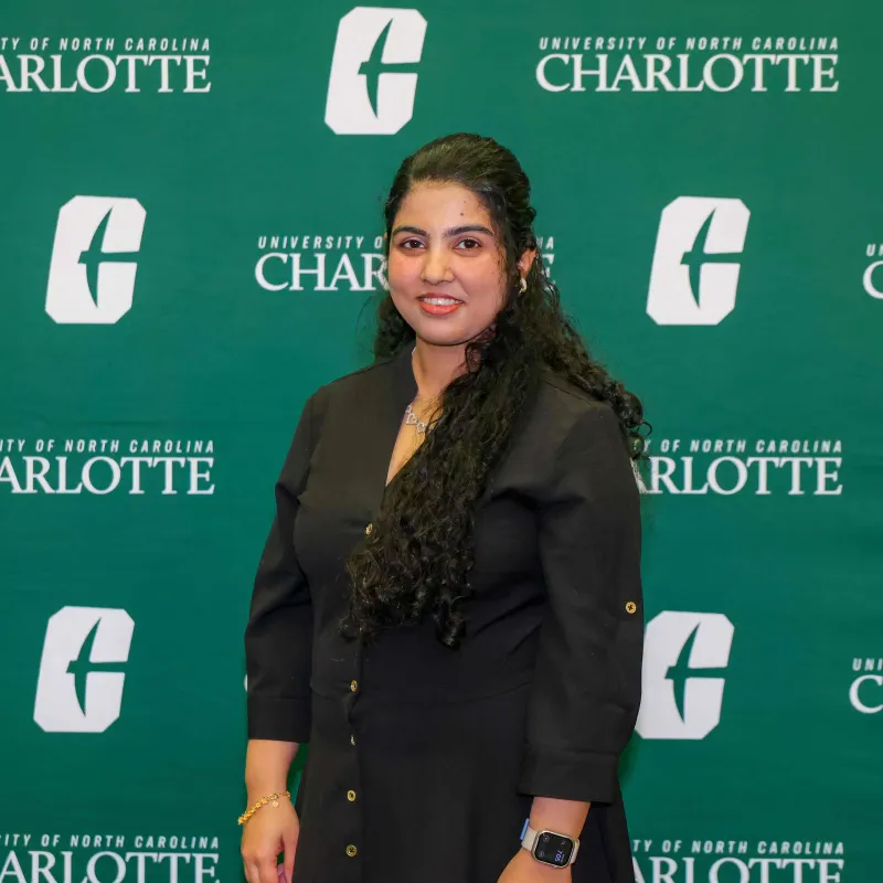 Nita Khanal smiling in front of a UNC Charlotte backdrop